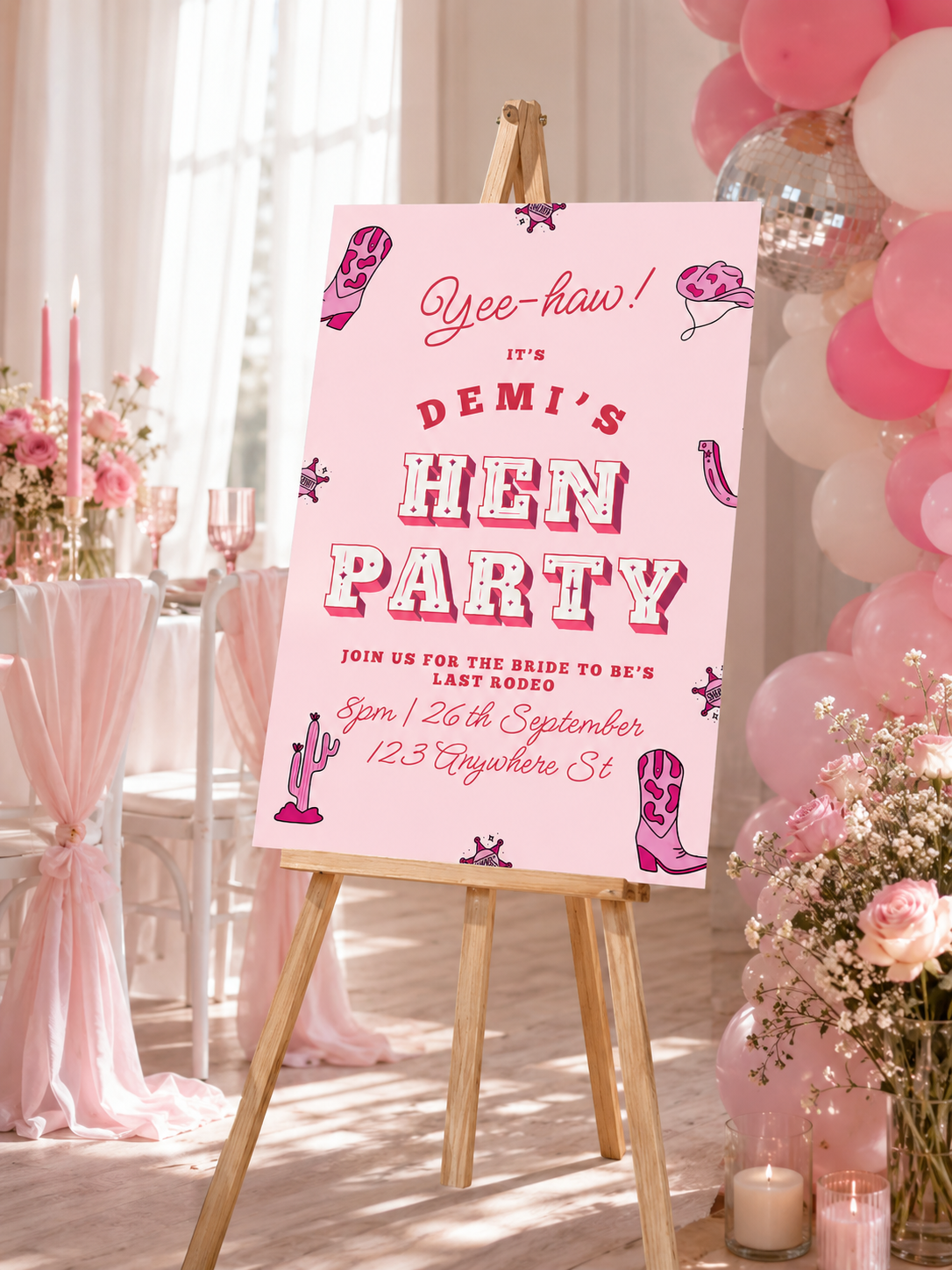A pink Western-themed bridal shower invitation sign on a wooden easel, surrounded by pink balloons, floral arrangements, and a decorated party setting.